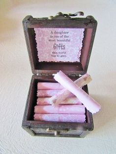 an open box with pink candles inside on a white tableclothed surface, next to a quote