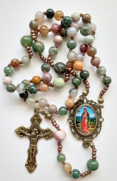 Handcrafted rosary made with 6 & 8mm natural Indian Agate gemstone beads. Hand knotted on cord along with small glass beads. Bronze tone crucifix is from Italy. Centerpiece has an image of Our Lady of Guadalupe. Approx. 17.5" Catholic rosary, 5 decades. Handmade Rosary, Mother Mary Images, Ceramic Framed, Indian Agate, Wire Jewelry Designs, Our Lady Of Guadalupe, Catholic Rosary, Lady Of Guadalupe, Jewelry Lookbook