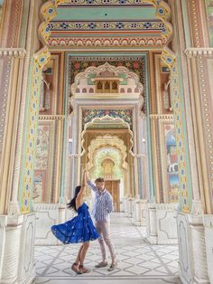 two people dancing in an ornate building with colorful walls and arches, one holding the other's hand