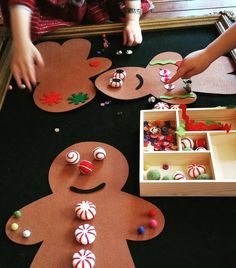 two children are making gingerbread cutouts out of paper with candy and candies