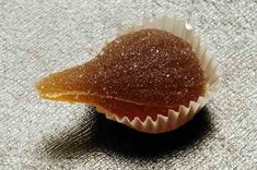 a piece of food sitting on top of a table next to a cup filled with sugar