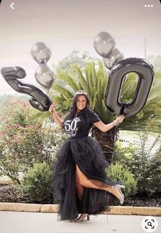 a woman in a black dress is holding balloons that spell out the number 50,