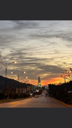 cars are driving down the street at sunset