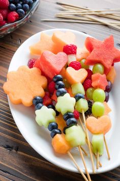 fruit skewers are arranged on a white plate