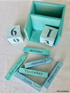 wooden blocks spelling the days of the week in front of a blue box with numbers