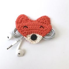 a crocheted animal earbud holder with headphones on top of it