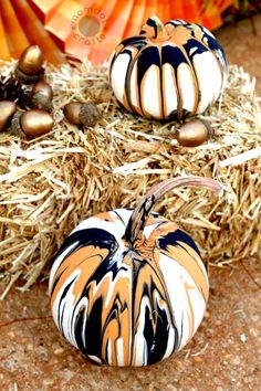 two painted pumpkins sitting on top of hay