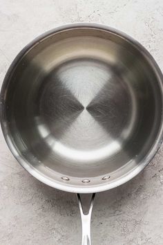 a stainless steel frying pan sitting on top of a white counter next to a wall