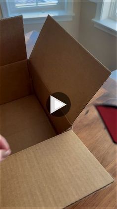 an open cardboard box on the floor with someone opening it