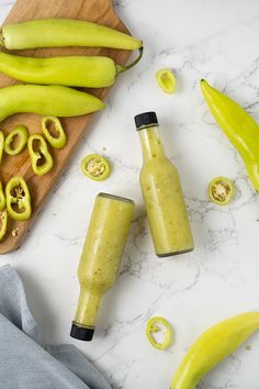 two bottles filled with green smoothie next to sliced jalapenos