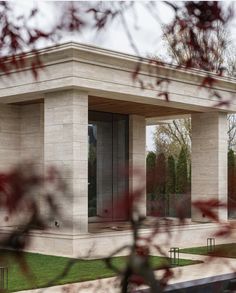 an outdoor pavilion with glass doors on the sides and grass in the foreground, surrounded by trees