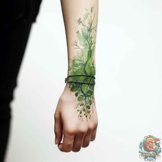 a woman's arm with a green tattoo on it and leaves around the wrist