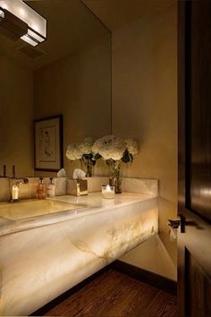 a bathroom sink sitting under a mirror next to a wooden counter top with flowers on it