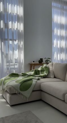 a living room with a couch, rug and window curtained windows in the background