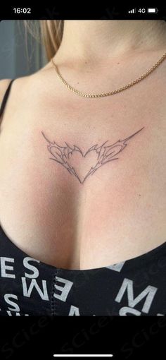 a woman's chest with two hands holding a heart tattoo on her left side