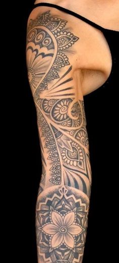 a woman's leg with tattoos on it and an intricate flower design in the middle