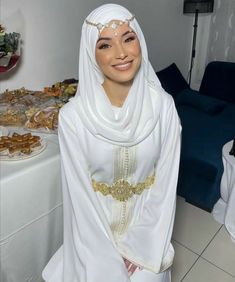 a woman wearing a white hijab standing in front of a table