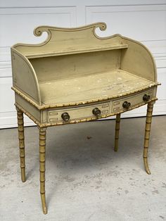 an old desk has been painted white with gold trimmings and is sitting in front of a garage door