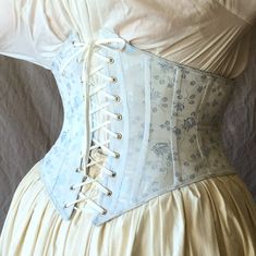 "Our popular c. 1900 Lilly waist cinch corset in your choice of brocade. This style recreates the under-bust corset shape popular from the 1870s to the turn of the 19th century. It defines a lovely curved waist with boning on the seams without affecting the natural shape of the bust. There is a center front busk opening and a graceful point at the top and bottom edges in both the front and the back. Available in size Small-2XL or custom sized up to 4XL Size chart available here or select \"custo Regency Style Overbust Corset Dress, Regency Corset Dress With Fitted Bodice, Regency Style Fitted Bodice With Corset Back, Regency Style Wedding Corset With Historical Design, Regency Style Historical Wedding Corset, Regency Underbust Corset With Fitted Bodice, Regency Style Overbust Corset With Fitted Bodice, Regency Style Underbust Corset Dress With Fitted Bodice, Regency Style Overbust Fitted Corset