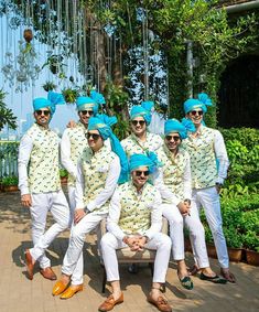 a group of men dressed in white and blue outfits posing for a photo together on a bench