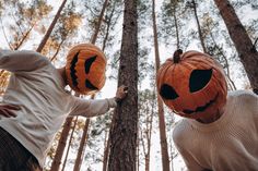 two people holding pumpkins with faces carved into them