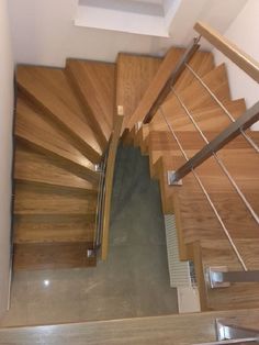 an overhead view of a wooden staircase with metal handrails and wood treading