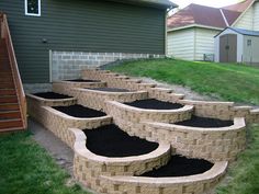 an outdoor area with steps made out of bricks and black soil in the middle, next to a house