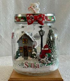 a glass jar filled with snow and christmas decorations