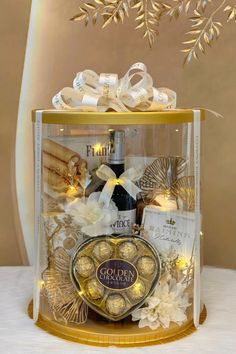 a glass box filled with lots of different types of chocolates and wine bottles on top of a table