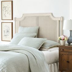 a bed with white sheets and pillows in a bedroom next to a lamp on a dresser