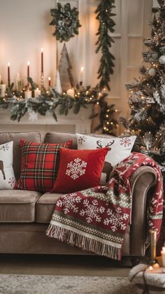 a living room decorated for christmas with red and white pillows on the couch, candles and garlands