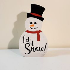 a wooden snowman with a hat and scarf on it's head that says let it snow