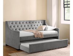 a gray daybed sitting on top of a hard wood floor next to a window