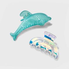 two pieces of glass sitting next to each other on a white surface and one piece is shaped like a dolphin