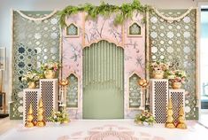 an elaborately decorated stage set up with flowers and greenery on the side wall