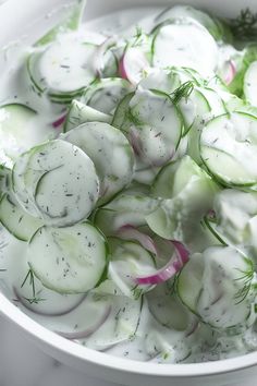 a white bowl filled with cucumbers and onions