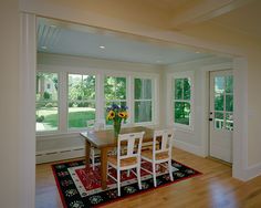 a table and chairs in a room with large windows on both sides of the room