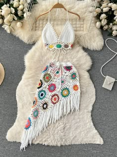 two pieces of white fur with multicolored flowers and fringes on it, next to a straw hat