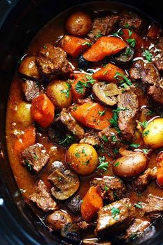 a crock pot filled with beef stew and potatoes, garnished with parsley