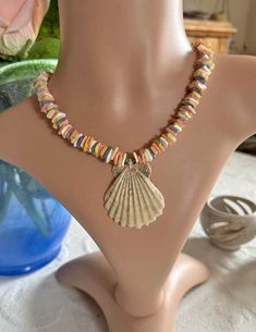 Step into the spirit of summer with our delightful necklace adorned with colorful seashell chips, accented by a charming small scallop shell centerpiece. The shell is meticulously washed and treated with a protective varnish, ensuring both durability and lasting beauty. Measuring approximately 40 cm (16 inches) with a 5 cm extension chain, this versatile piece perfectly captures the essence of the oceanic theme and is ideal for the summer trend of 2024.  Whether you're dressing up for a beach pa Multicolor Shell-shaped Jewelry For Beach, Multicolor Shell Jewelry For Vacation, Shell-shaped Beaded Necklace For Beach, Multicolor Shell For Vacation, Bohemian Multicolor Shell-shaped Jewelry, Multicolor Beaded Shell, Multicolor Vacation Shell-shaped Shell, Beachy Beaded Shell-shaped Necklace, Multicolor Strand Shell Necklace For Vacation