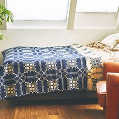 a bed with a blue blanket sitting on top of it next to a brown chair