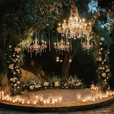 an outdoor ceremony with candles and chandeliers on the ground, surrounded by greenery