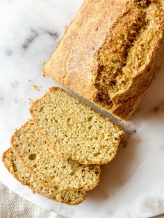 a loaf of bread sitting on top of a white plate next to a slice of bread