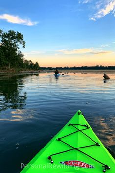 a green kayak is in the water at sunset