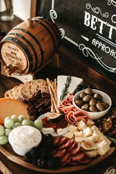 an assortment of cheeses, meats and crackers on a wooden platter