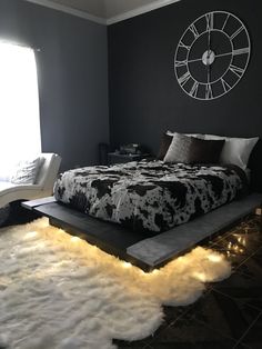 a bed with lights on the floor and a clock mounted to the wall above it