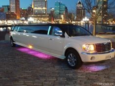 a white limo parked in front of a cityscape at night with the lights on