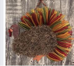 a colorful wreath hanging on the side of a wooden wall next to an orange turkey