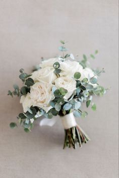 a bridal bouquet with white flowers and greenery on the top is ready to be used as a bride's bouquet