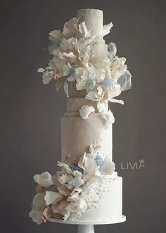 a three tiered wedding cake with flowers on top